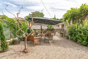 A patio area with a table and chairs, a large umbrella, and potted plants. - La maison d'à côté, charming town house near Mont Ventoux (Carpentras)