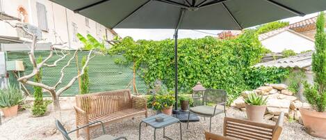 An outdoor patio with a wooden bench, a table, and an umbrella.