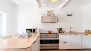 Une cuisine moderne dotée d’un îlot central, d’un four encastré et d’un luminaire suspendu.