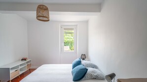 Une chambre à coucher avec un lit, une table de chevet, une lampe, une étagère et une fenêtre.