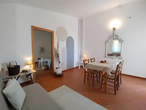 Un coin repas comprenant une table, des chaises, une lampe et un miroir au mur.