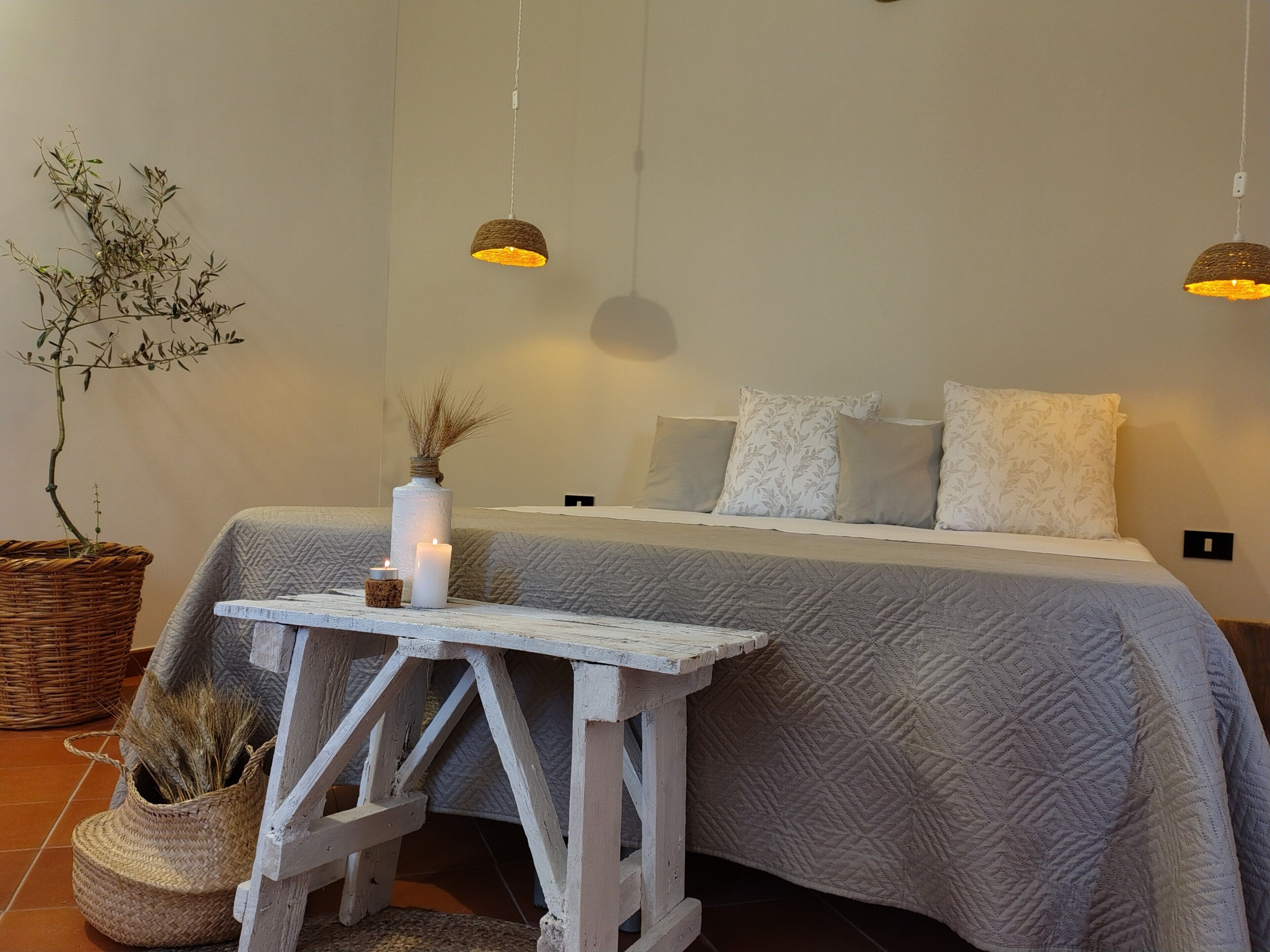 A bedroom with a bed, bedside table, lamp, and a potted plant.