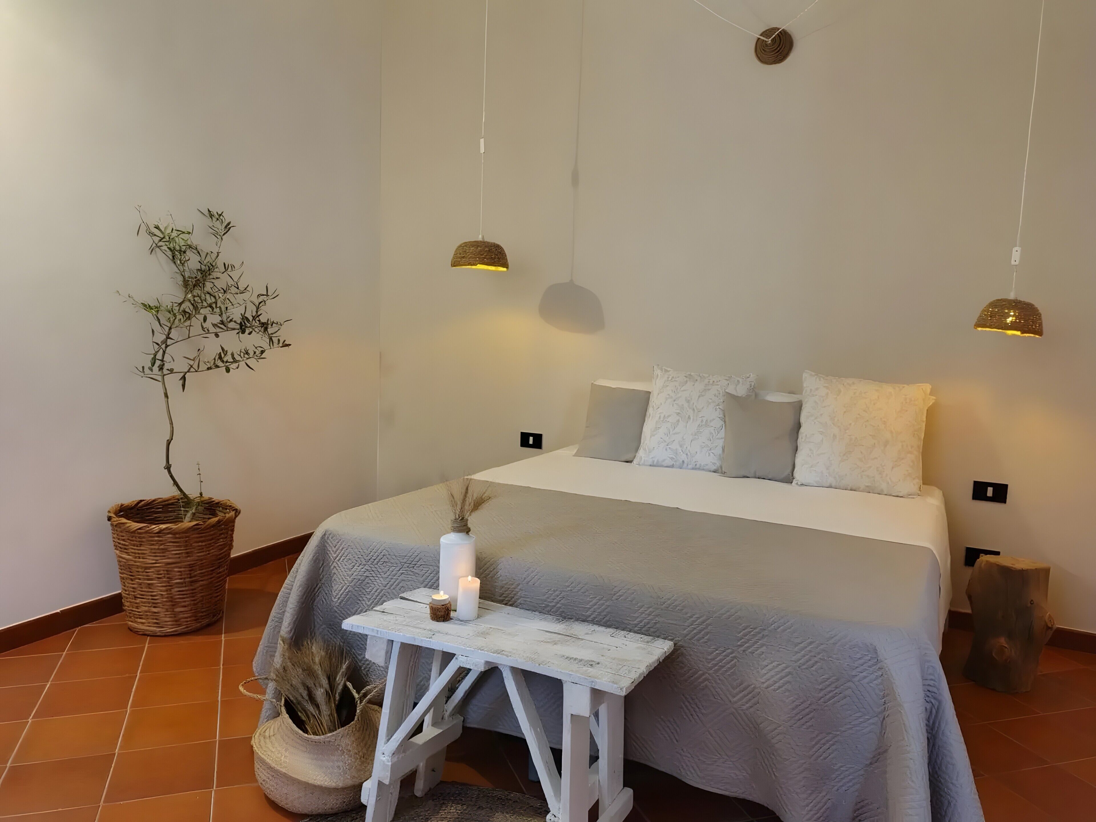 Une chambre à coucher avec un lit, des tables de chevet, une plante en pot et des lampes suspendues.