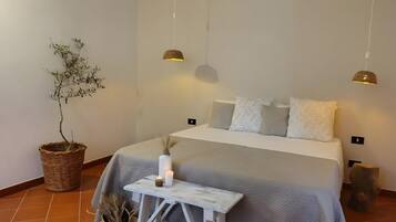 Une chambre à coucher avec un lit, des tables de chevet, une plante en pot et des lampes suspendues.