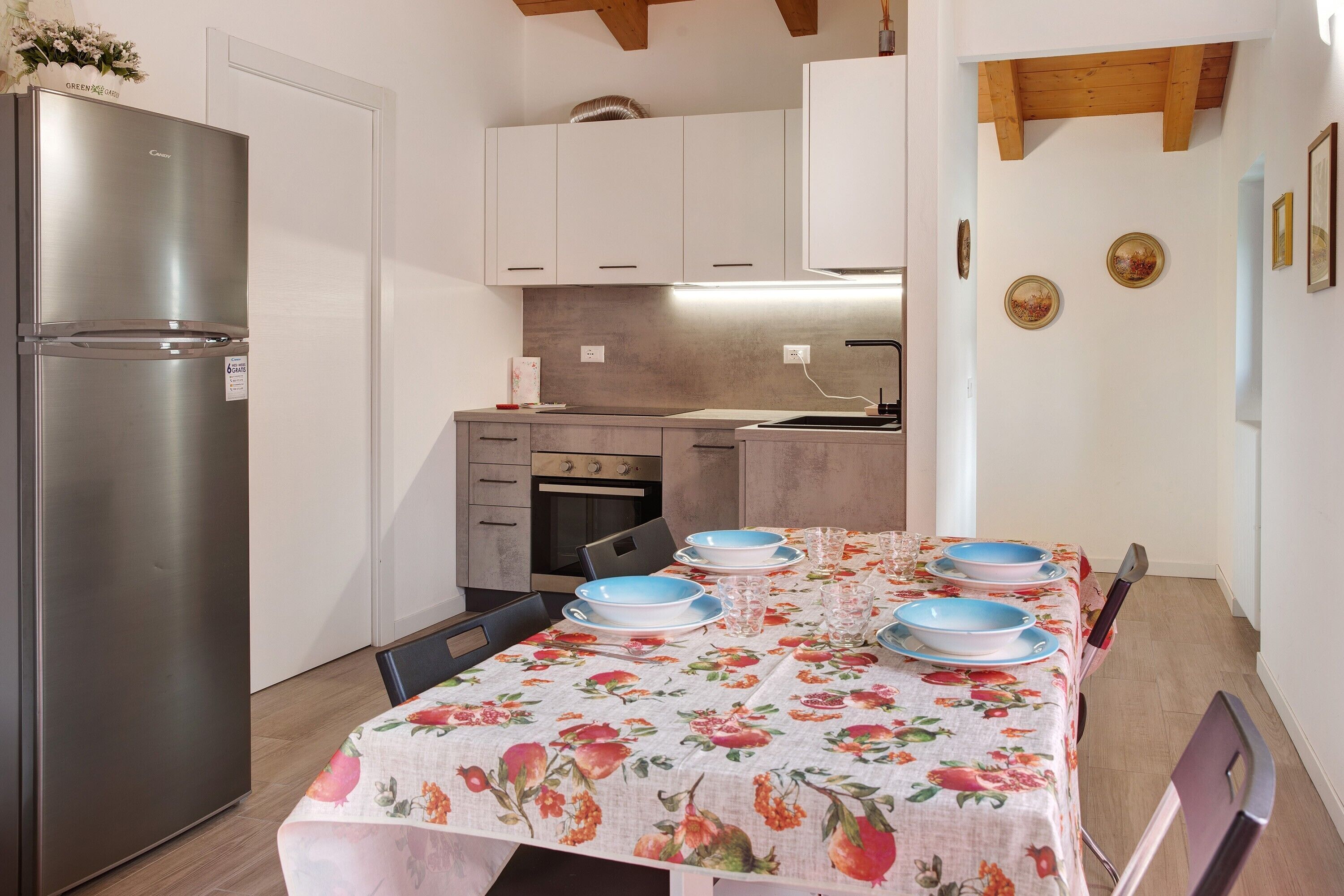 A kitchen with a refrigerator, oven, and dining table set with plates and glasses.