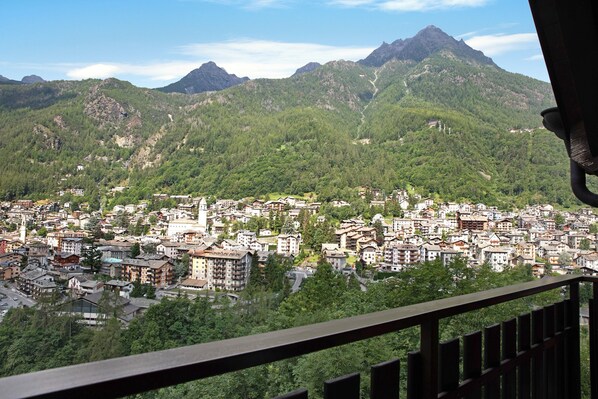 A town with a mountainous backdrop, featuring dense greenery and a variety of buildings.