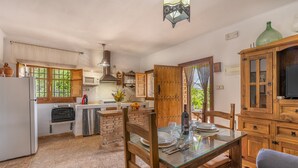 A kitchen with a dining area, a refrigerator, a microwave, a sink, and wooden cabinets.