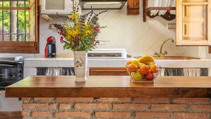 A kitchen with a brick island, a microwave, a stove, and a sink.