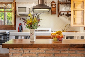 A kitchen with a brick island, a microwave, a stove, and a sink. - Vacation Home "La Terrera" with Mountain View, Private Pool & Wi-Fi (Órgiva)