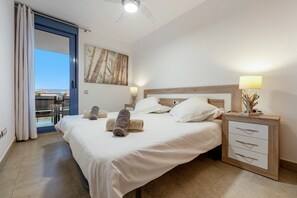 Une chambre d’hôtel avec un lit, une table de chevet, une lampe, un tableau et une vue sur l’extérieur, visible à travers une porte.