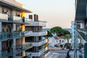 A multi-story residential building with balconies, a street view, and a body of water in the background. - Apartment 'Cambrils Platja' with Shared Pool, Wi-Fi and Air Conditioning (Cambrils)