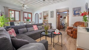 Una sala de estar con un sofá modular, una mesa de centro, un sillón de cuero y un ventilador de techo.