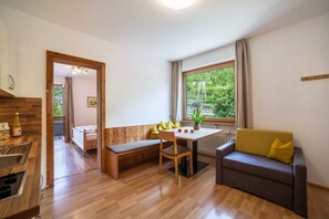 Une cuisine moderne avec des meubles de rangement en bois, une table à manger avec des chaises, un banc et un canapé avec des coussins.
