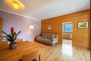 Un intérieur moderne avec une table à manger en bois, un canapé et une plante en pot.