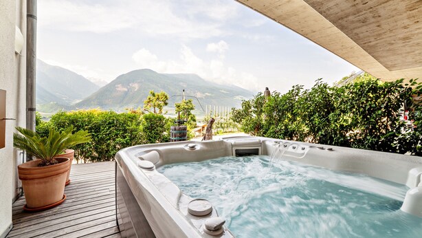 A hot tub with a mountain view, wooden deck, and potted plants. - Apartment "Langstein Rose" with Mountain View, Balcony and Wi-Fi (Coldrano)