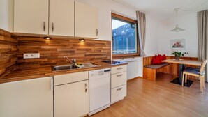 A modern kitchen with wooden cabinetry, a dishwasher, and a window with a view of mountains. - Apartment "Langstein Rose" with Mountain View, Balcony and Wi-Fi (Coldrano)