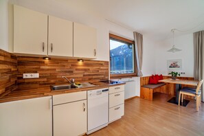 Una cocina moderna con armarios de madera, lavavajillas y ventana con vistas a montañas.
