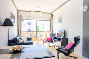 Una sala de estar moderna con un sofá, un escritorio con computadora, una mesa de juegos y una silla.