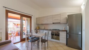 Una cocina moderna con comedor, refrigerador y puerta corrediza de vidrio que da a un patio exterior.