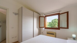 Un dormitorio con cama, ventana con vistas, radiador y puerta.