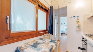 A compact kitchen with a table, a chair, and a window with curtains.