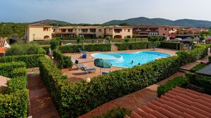 A hotel with a swimming pool, surrounded by well-maintained hedges and a mountain backdrop. - Apartment 'Casa Vacanze Fragola' with Shared Pool, Private Terrace and Air Conditioning (olbia)