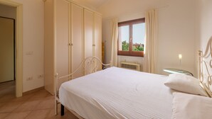 A bedroom with a bed, a wardrobe, a window, and a radiator. - Apartment 'Casa Vacanze Fragola' with Shared Pool, Private Terrace and Air Conditioning (olbia)