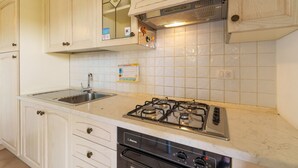 A kitchen with white cabinets, a stainless steel sink, a gas stove, and a dishwasher. - Apartment 'Casa Vacanze Fragola' with Shared Pool, Private Terrace and Air Conditioning (olbia)