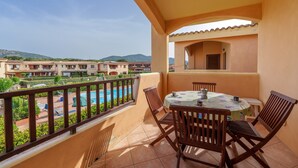 A balcony with a table and chairs, overlooking a swimming pool and buildings. - Apartment 'Casa Vacanze Fragola' with Shared Pool, Private Terrace and Air Conditioning (olbia)