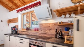 A modern kitchen with a built-in oven, a coffee maker, and wooden shelves.