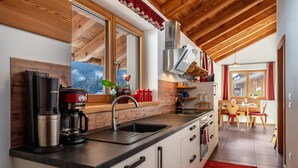 A modern kitchen with a built-in stove, a sink, and a window overlooking a snowy landscape.
