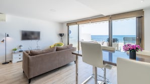 A modern living room with a sofa, a TV, a table, and a view of the sea. - Apartment 'Top First Line  Altea' with Sea View, Wi-Fi and Air Conditioning (Altea)