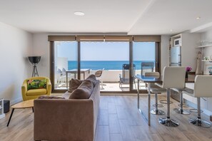 Una sala moderna con sofá, sillón amarillo y comedor con taburetes de bar.