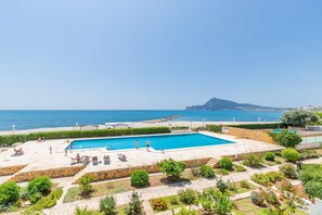 A swimming pool with a view of the sea, surrounded by greenery and a stone patio. - Apartment 'Top First Line  Altea' with Sea View, Wi-Fi and Air Conditioning (Altea)