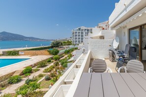Un balcon avec une piscine, un espace salon extérieur et une vue sur la mer et les bâtiments.