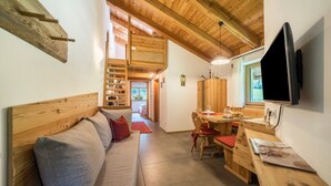 A cozy room with a wooden ceiling, a sofa with cushions, a dining table with chairs, and a flat-screen TV mounted on the wall. - Holiday Apartment "Larch Soge Apt Helmuth" with Mountain View, Balcony & Shared Garden (Racines)