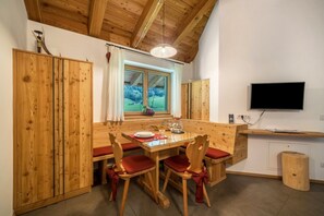 Un coin repas en bois avec une table et des chaises, une fenêtre donnant sur un beau paysage et un téléviseur fixé au mur.