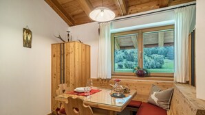 A wooden dining area with a table, chairs, and a bench. A window with a view of greenery is visible. - Holiday Apartment "Larch Soge Apt Helmuth" with Mountain View, Balcony & Shared Garden (Racines)