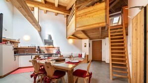 A wooden interior with a dining table, chairs, a kitchen, and a staircase. - Holiday Apartment "Larch Soge Apt Paula" with Mountain View, Private Terrace & 2 Balconies (Racines)