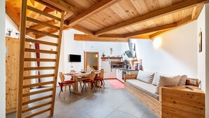 A wooden interior with a dining area, kitchen, and a sofa. - Holiday Apartment "Larch Soge Apt Paula" with Mountain View, Private Terrace & 2 Balconies (Racines)