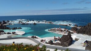 A coastal resort with multiple swimming pools, rocky formations, and clear blue waters.