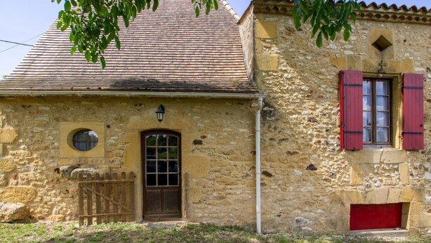 A stone building with a tiled roof, a wooden door, and a small window with shutters. - Country House with Large Garden, Family Room, and Pet-Friendly in Perigord (Montferrand-du-Périgord)