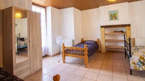 A bedroom with a wooden ceiling, a bed with a blue bedspread, a wooden wardrobe, a bedside table, and a radiator. - Country House with Large Garden, Family Room, and Pet-Friendly in Perigord (Montferrand-du-Périgord)