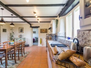 A cozy kitchen with wooden furniture, a dining area, and a view of the garden.