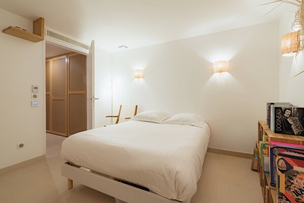 A bedroom with a bed, bedside tables, a wardrobe, and wall-mounted lights. - Duplex Dreams, by Veeve (Paris)