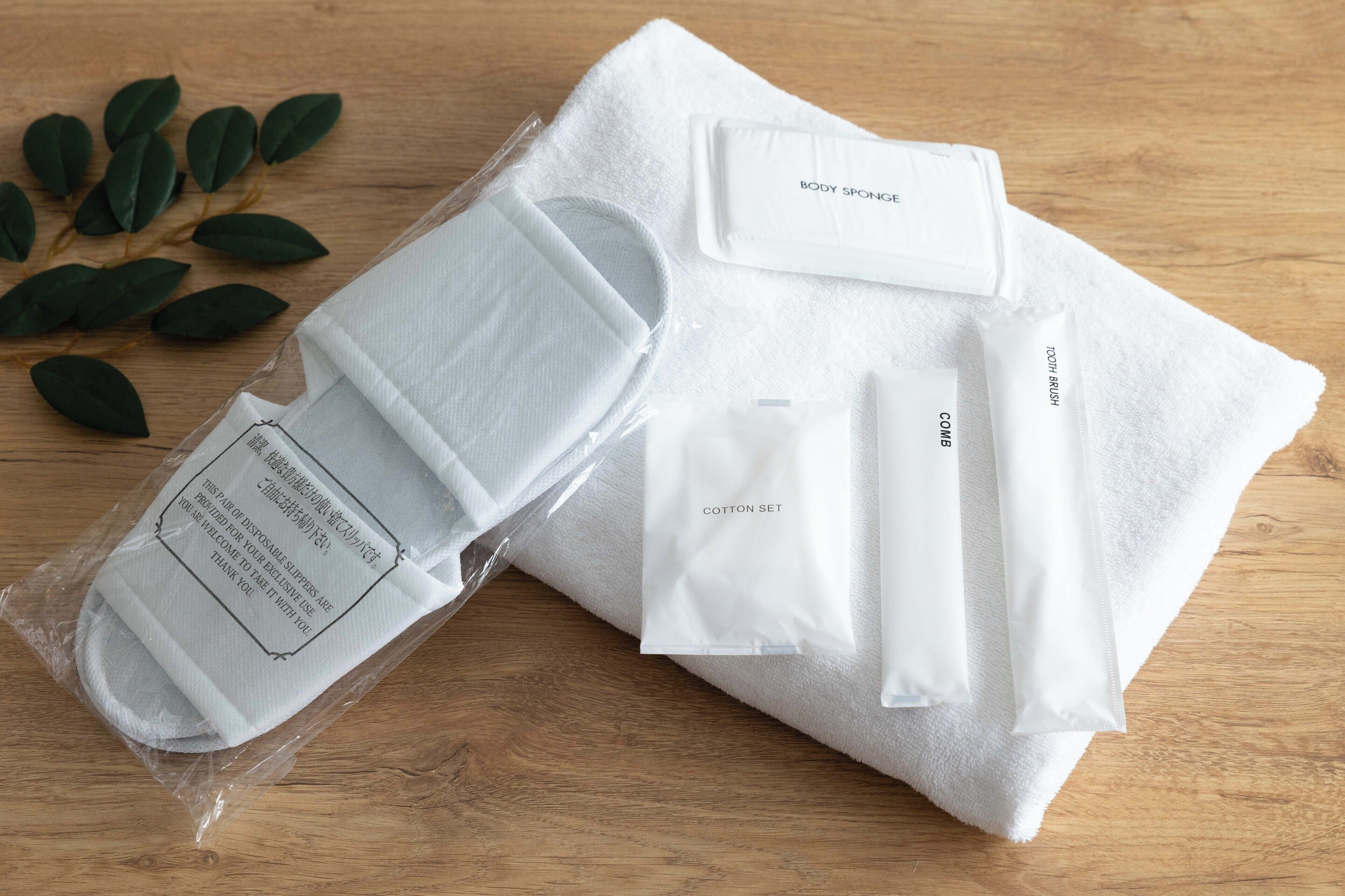 A neatly arranged set of white cotton sets, including a body sponge, on a wooden surface.