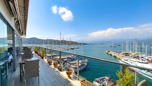 A balcony with potted plants, overlooking a marina with boats and a clear blue sky. - Dedeoğlu Port Hotel (Fethiye)