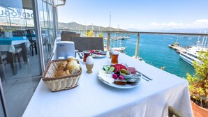 A table set with food and drinks on a balcony overlooking a marina with boats. - Dedeoğlu Port Hotel (Fethiye)