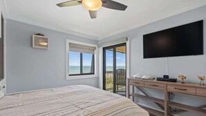 A bedroom with a bed, a desk, a TV, and a balcony with a view of the ocean. - Ocean Forest Villas C310 - Oceanfront (Myrtle Beach)