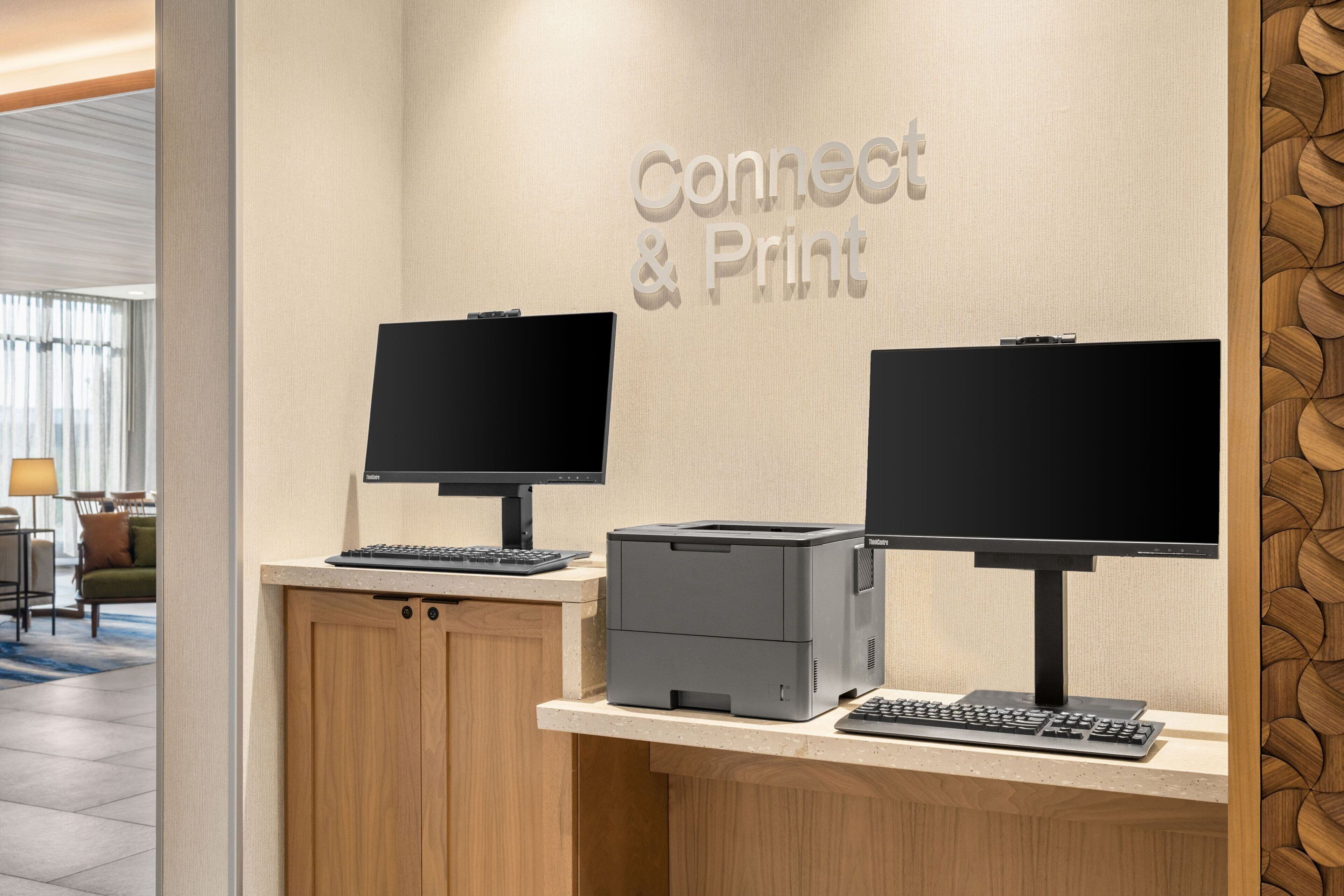 A reception desk with two monitors, a printer, and a keyboard.